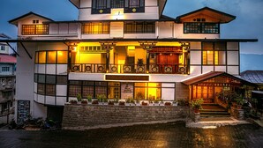 A two-story building with a traditional architectural style, featuring a balcony with wooden railings and potted plants. - Treenz Lite (Gangtok)