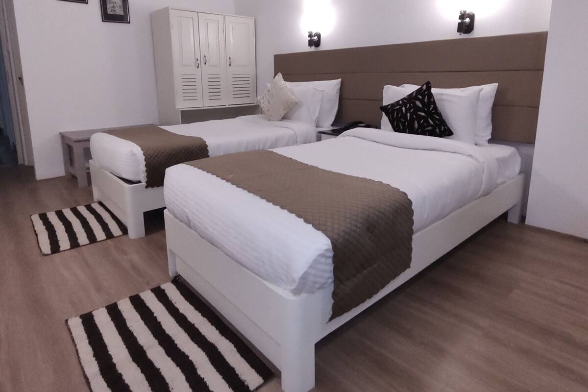 A hotel room with two beds, a wardrobe, and a nightstand.