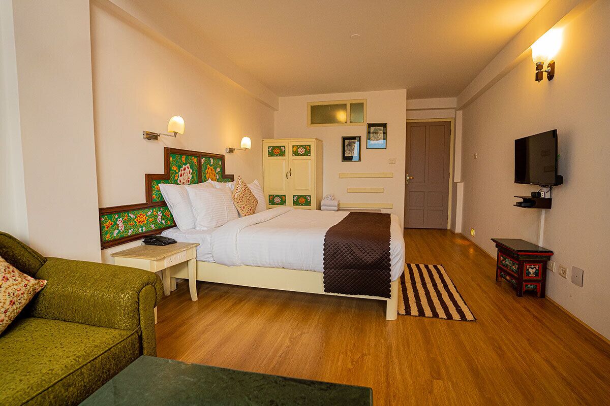 A bedroom with a bed, bedside tables, a television, and a wardrobe.
