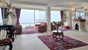 A spacious living room with a large window, a fireplace, and a balcony with a view. - Treenz Lite (Gangtok)