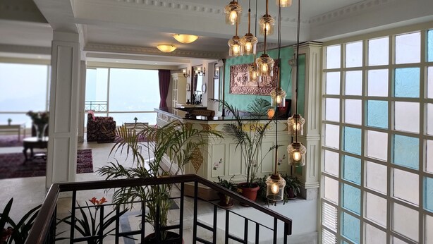 A spacious lobby with a staircase, large windows, and hanging pendant lights. - Treenz Lite (Gangtok)