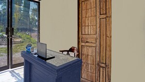 Un mostrador de recepción con una computadora portátil, una pequeña caja azul y una silla de madera.
