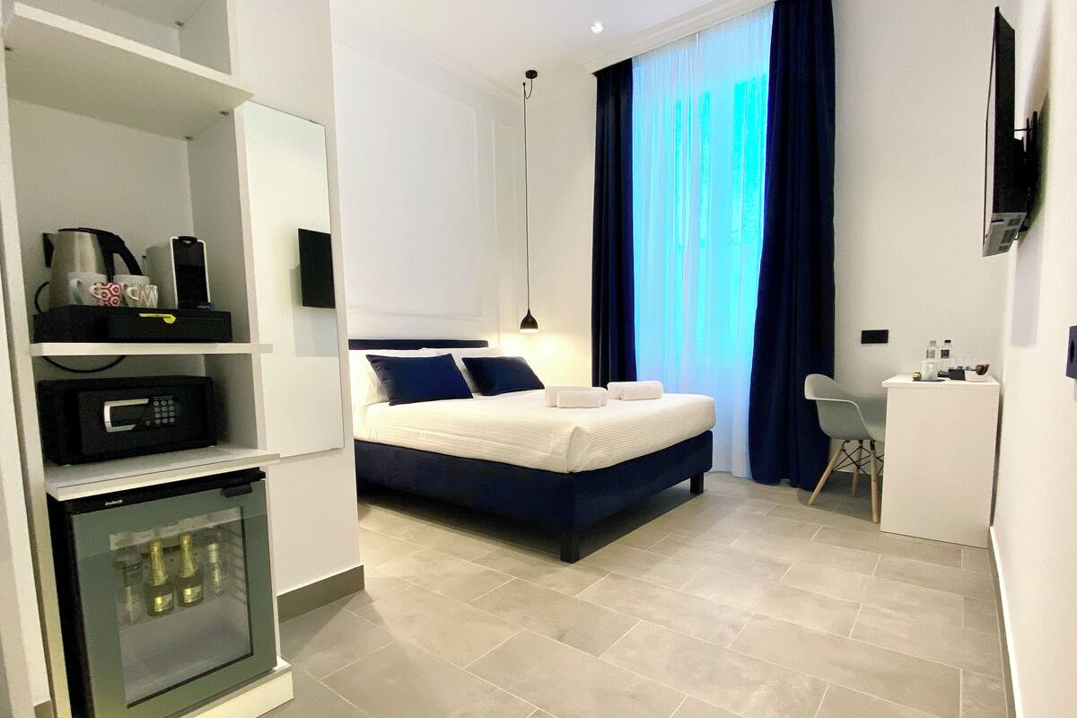 Une chambre d’hôtel moderne équipée d’un lit, d’un bureau, d’un mini-bar et d’une télévision.