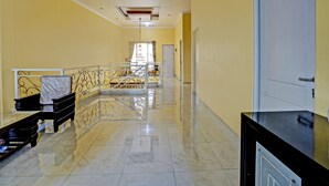 A hotel corridor with a marble floor, a staircase with a metal railing, and a door at the end. - Hotel O Raffa Residence Syariah (Surabaya)