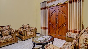 A traditional living room with a sofa set, a round coffee table, and a wooden wardrobe. - Hotel O Raffa Residence Syariah (Surabaya)
