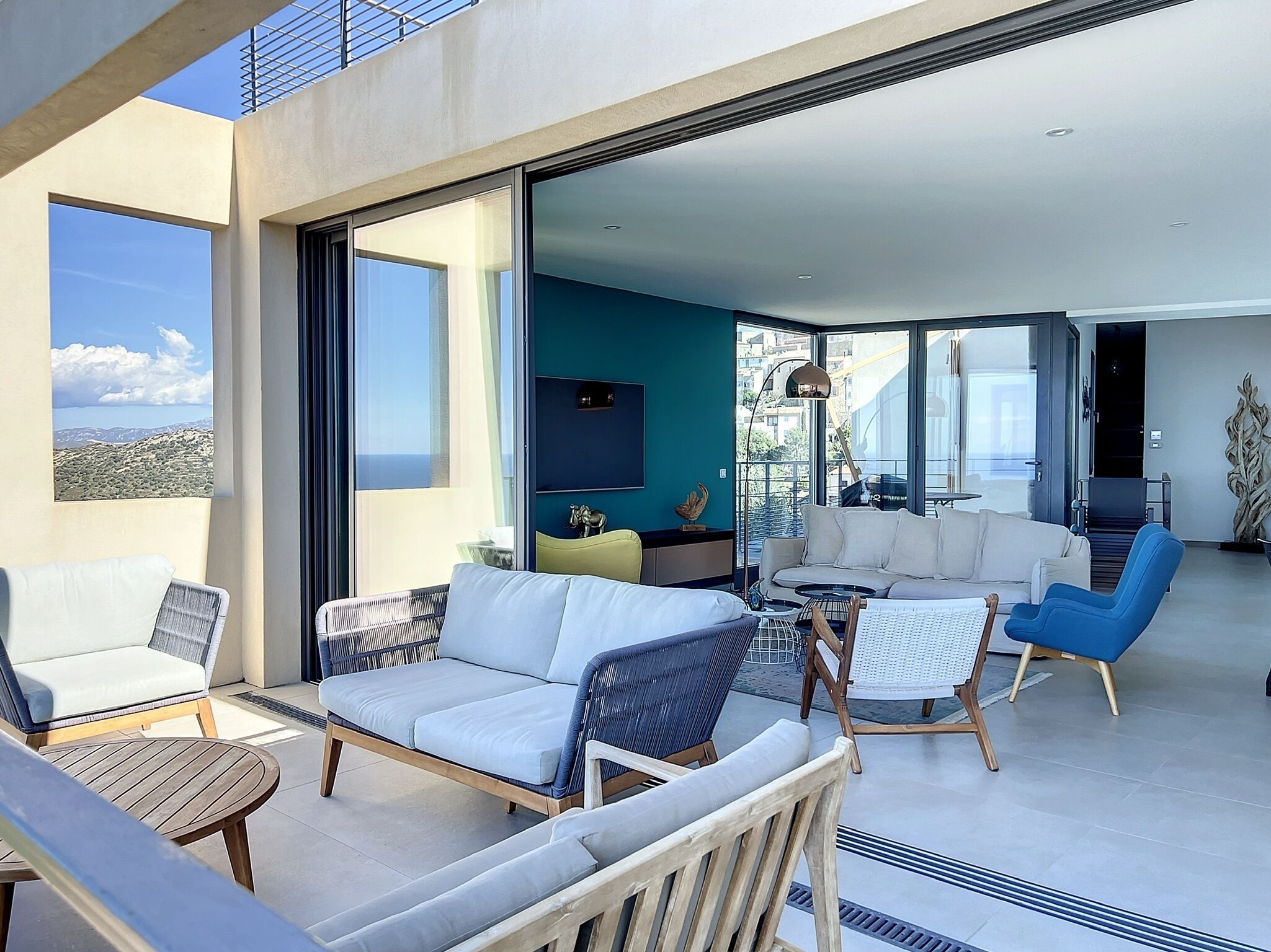 A modern living room with a sofa, chairs, and a coffee table. There is a large window with a view of the city.
