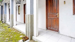 A row of white buildings with wooden doors and columns. - Hotel O Fun Guesthouse Syariah (Mojokerto)