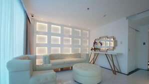 Una sala de estar moderna con un sofá seccional, un otoman redondo y un televisor montado en la pared.
