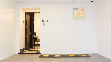 Un couloir avec une porte portant l’inscription « G6 » qui donne accès à une pièce. Il y a une petite fenêtre sur le mur et une bande de revêtement de sol tactile noire et jaune sur le sol.