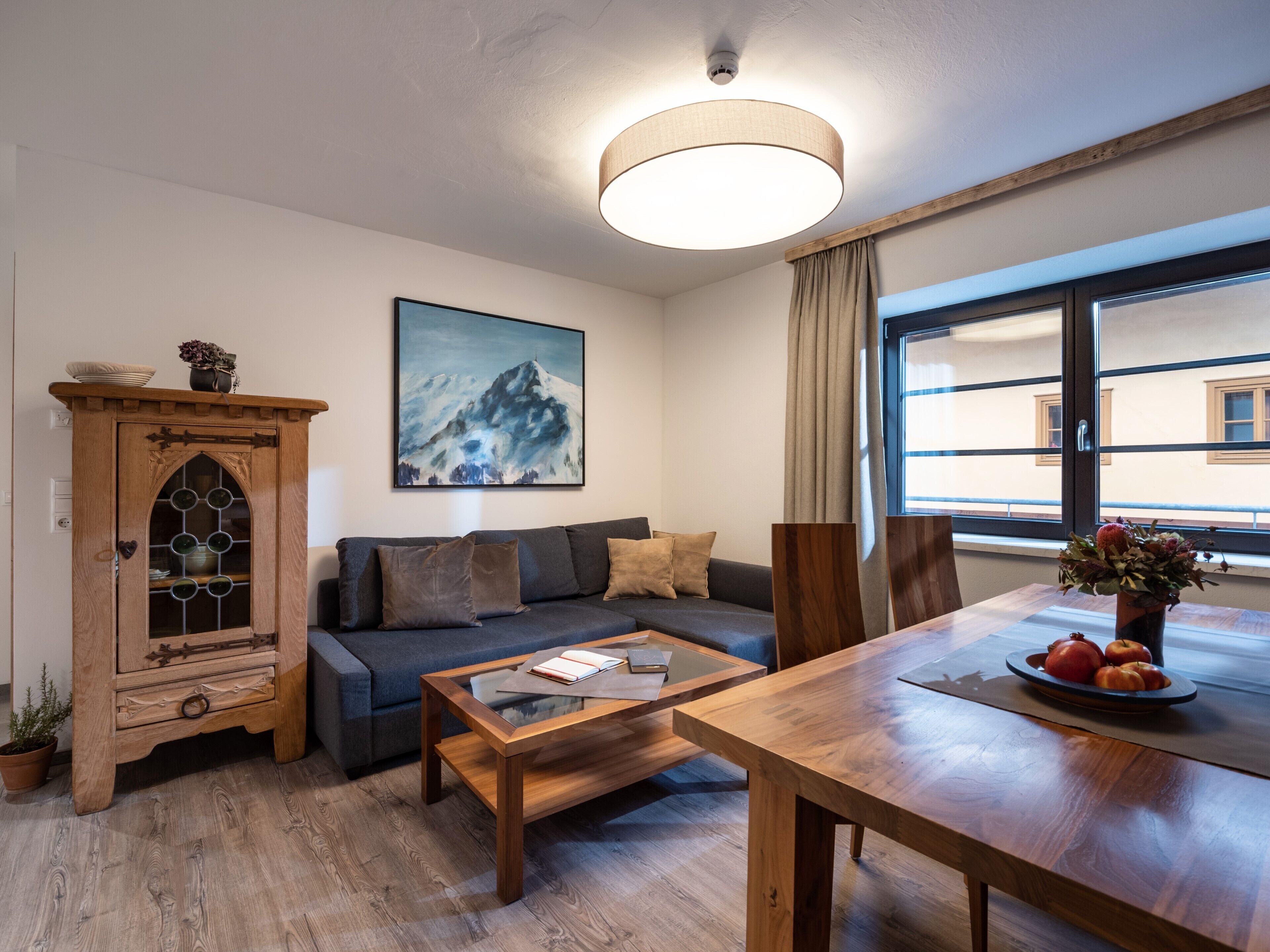 A modern living room with a wooden cabinet, a sofa, a coffee table, and a dining table.