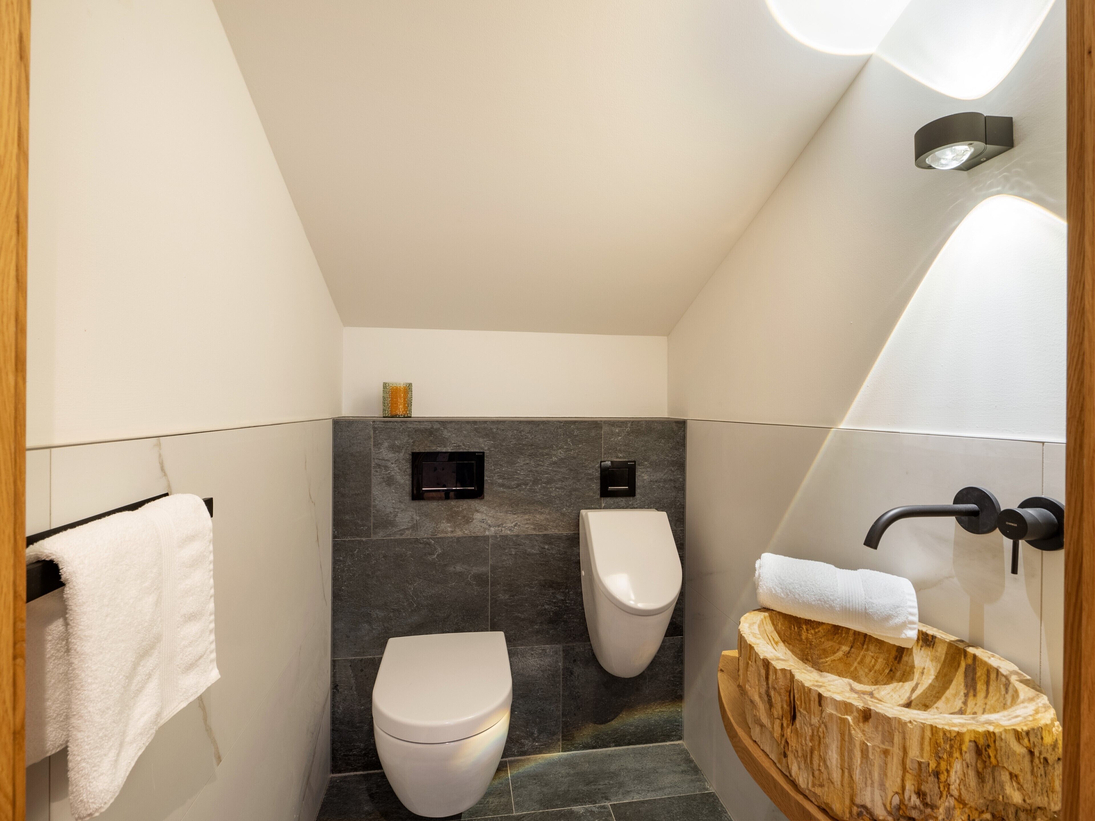 Un baño moderno con inodoro, bidé y lavamanos de madera.