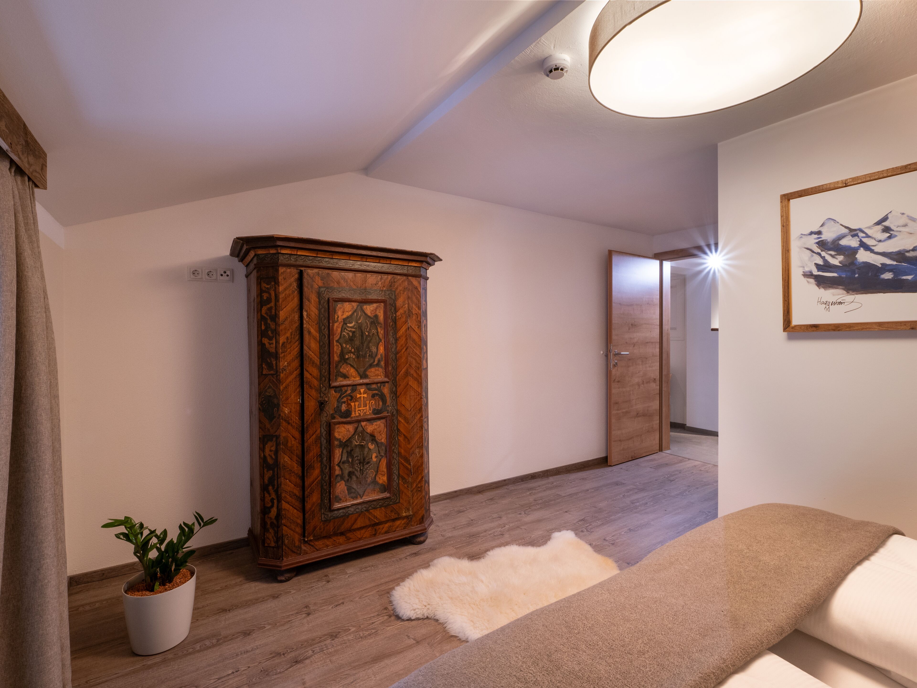 A modern living room with a wooden cabinet, a white rug, and a potted plant.