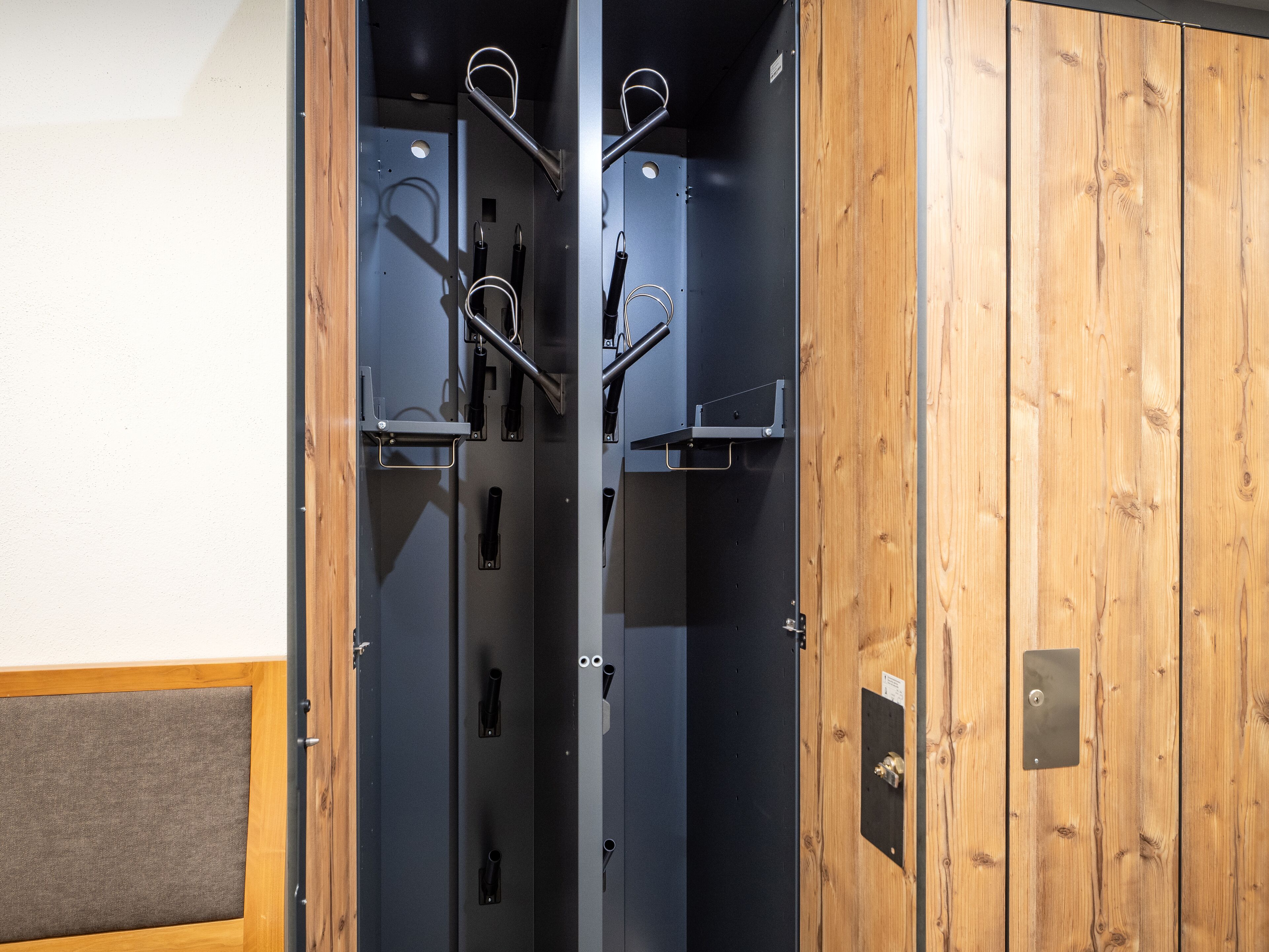 A room with a wooden door and a metal closet with multiple hooks.