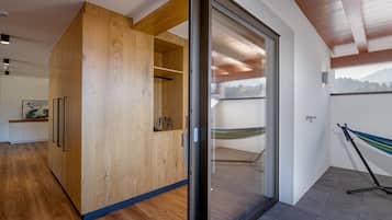A modern interior with a wooden wardrobe, a glass door leading to a balcony, and a hammock.