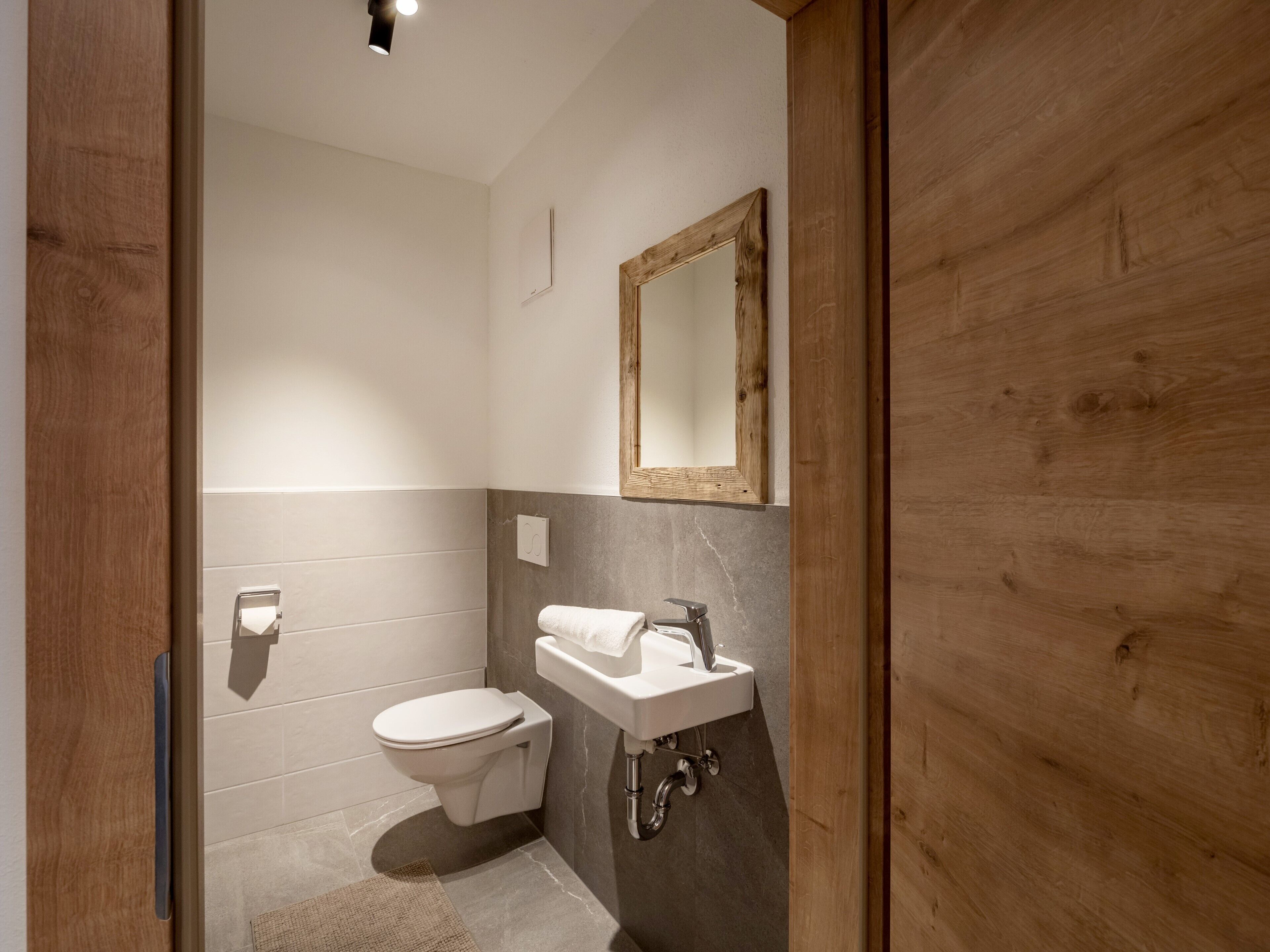 A modern bathroom with a toilet, sink, and mirror.