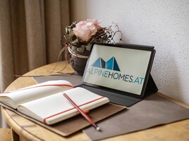 Una laptop sobre una mesa mostrando un sitio web, una libreta y un bolígrafo.