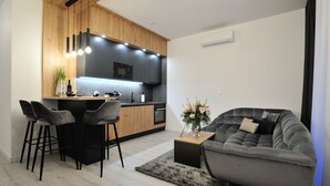 Eine moderne Küche mit Kochinsel, Barhocker und einem grauen Sofa.