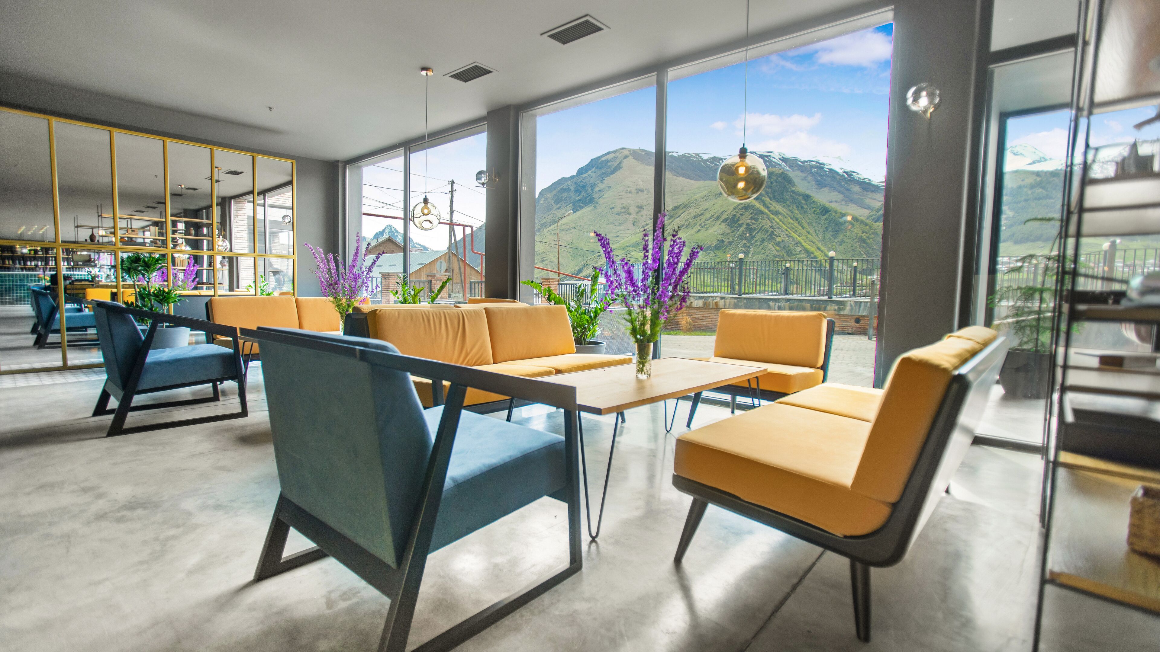Ein modernes Interieur mit Sitzgelegenheiten, Blick auf Berge und einer Bar.
