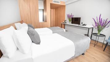 Habitación de hotel con dos camas, un escritorio, un televisor y un jarrón con flores.