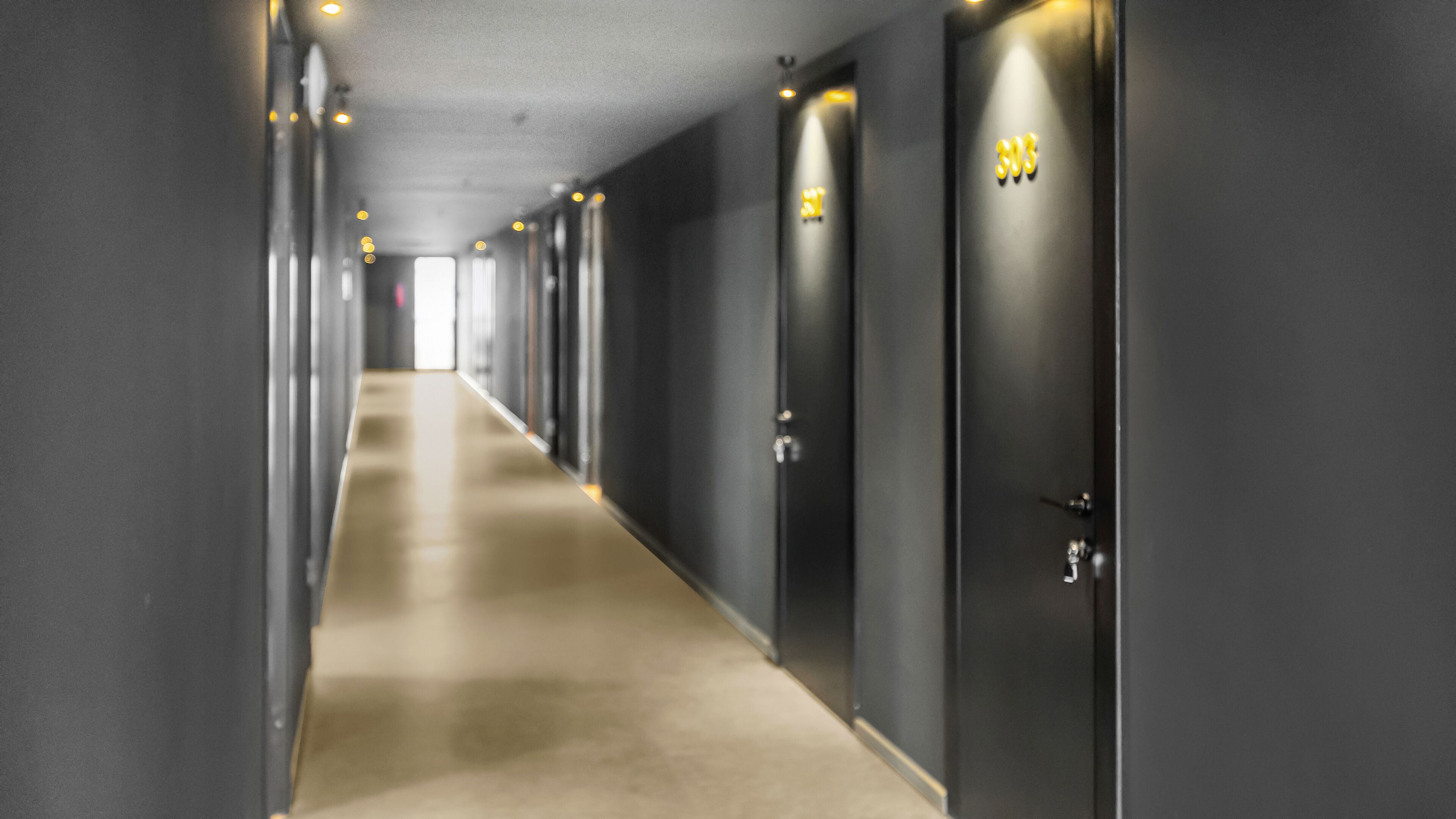 A long, narrow hallway with doors on both sides, leading to individual rooms.
