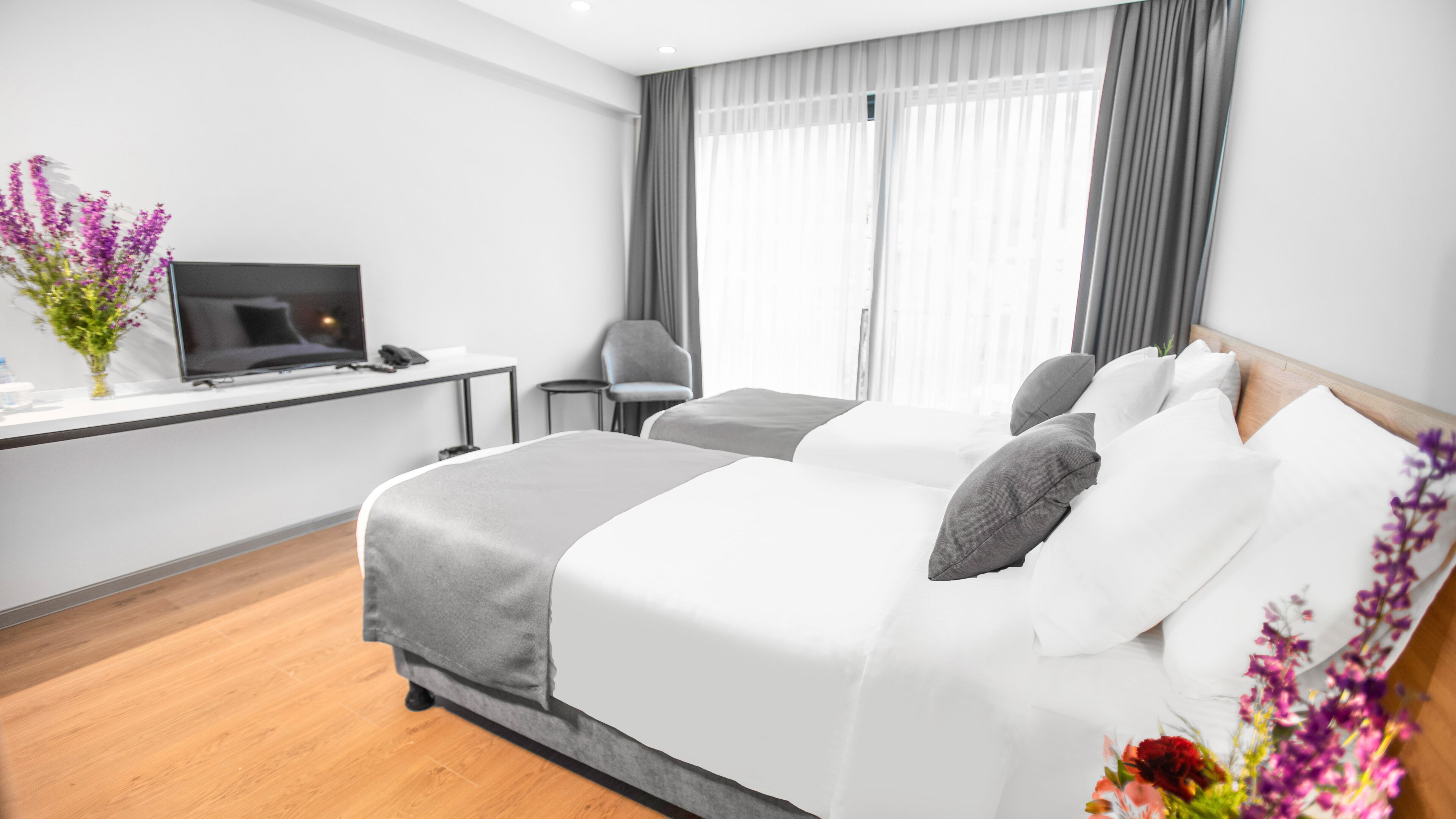 Una habitación de hotel moderna con una cama grande, un escritorio con ordenador y una silla.