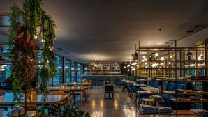 A modern restaurant with wooden tables and chairs, a bar area, and large windows. - Hotel Memoir Kazbegi (Kazbegi)