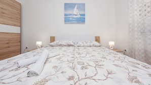 A bedroom with a bed, a painting of a sailboat, and two bedside lamps. - Villa Sea Pearl (Jasenice)