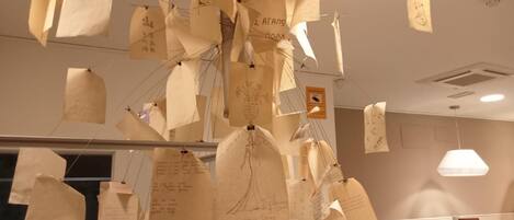 Une pièce où sont accrochées des feuilles et des notes, un panneau indiquant un secteur spécifique, et un comptoir d’accueil.