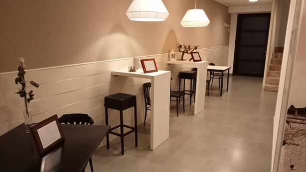 Un moderno vestíbulo de hotel con un mostrador de recepción, un área de descanso y una escalera que lleva a los pisos superiores.