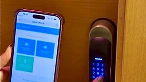 Una persona usando un teléfono inteligente para interactuar con una cerradura digital en una puerta.