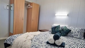 Une chambre à coucher comprenant un lit, une armoire, une table de chevet et un luminaire suspendu.