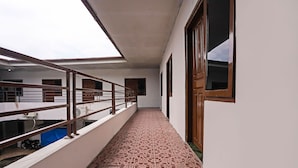 A corridor with a patterned floor, a metal railing, and a view of the sky through a skylight.