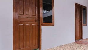 A hallway with two wooden doors, one with a window, and a tiled floor.