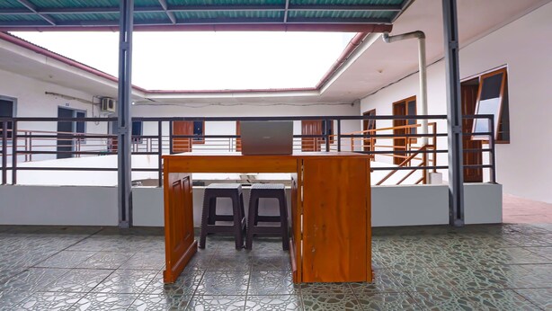 A spacious indoor area with a tiled floor, a wooden table with two stools, and a metal railing.