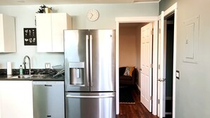 A modern kitchen with stainless steel appliances, a dishwasher, and a clock on the wall. - Bright, Beautiful & Dog Friendly Steps to Old Town (Fort Collins)