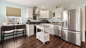 A modern kitchen with stainless steel appliances, white cabinetry, and a wooden floor. - Bright, Beautiful & Dog Friendly Steps to Old Town (Fort Collins)