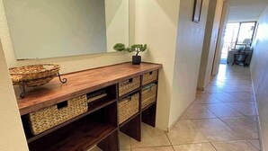 Un couloir avec une console en bois, des paniers en osier et une petite plante en pot.
