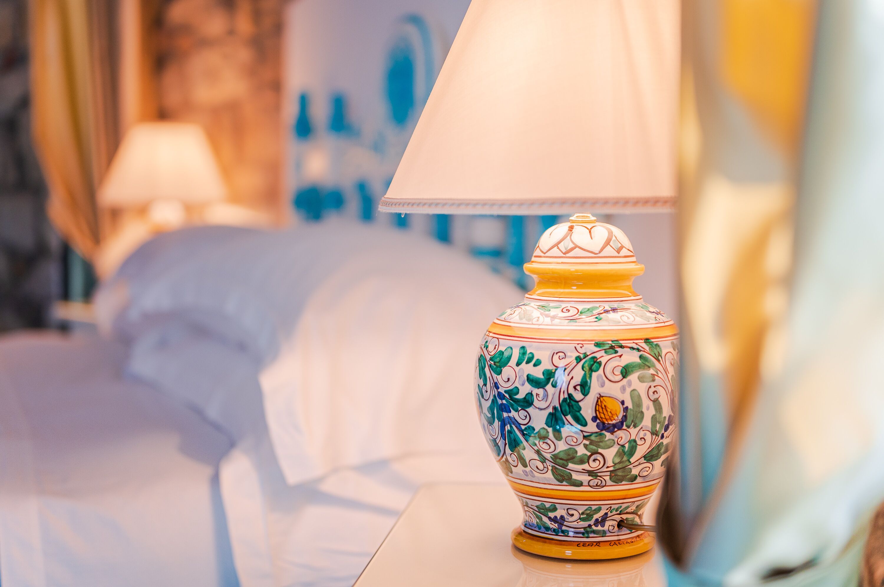 Una lampada decorativa con motivo floreale su un comodino in una camera d'albergo.
