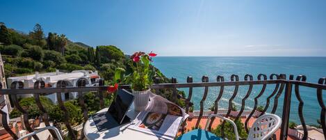 A balcony with a table, chairs, and a laptop.