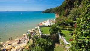 Une plage côtière aux eaux cristallines, avec un mur de pierres et des parasols.