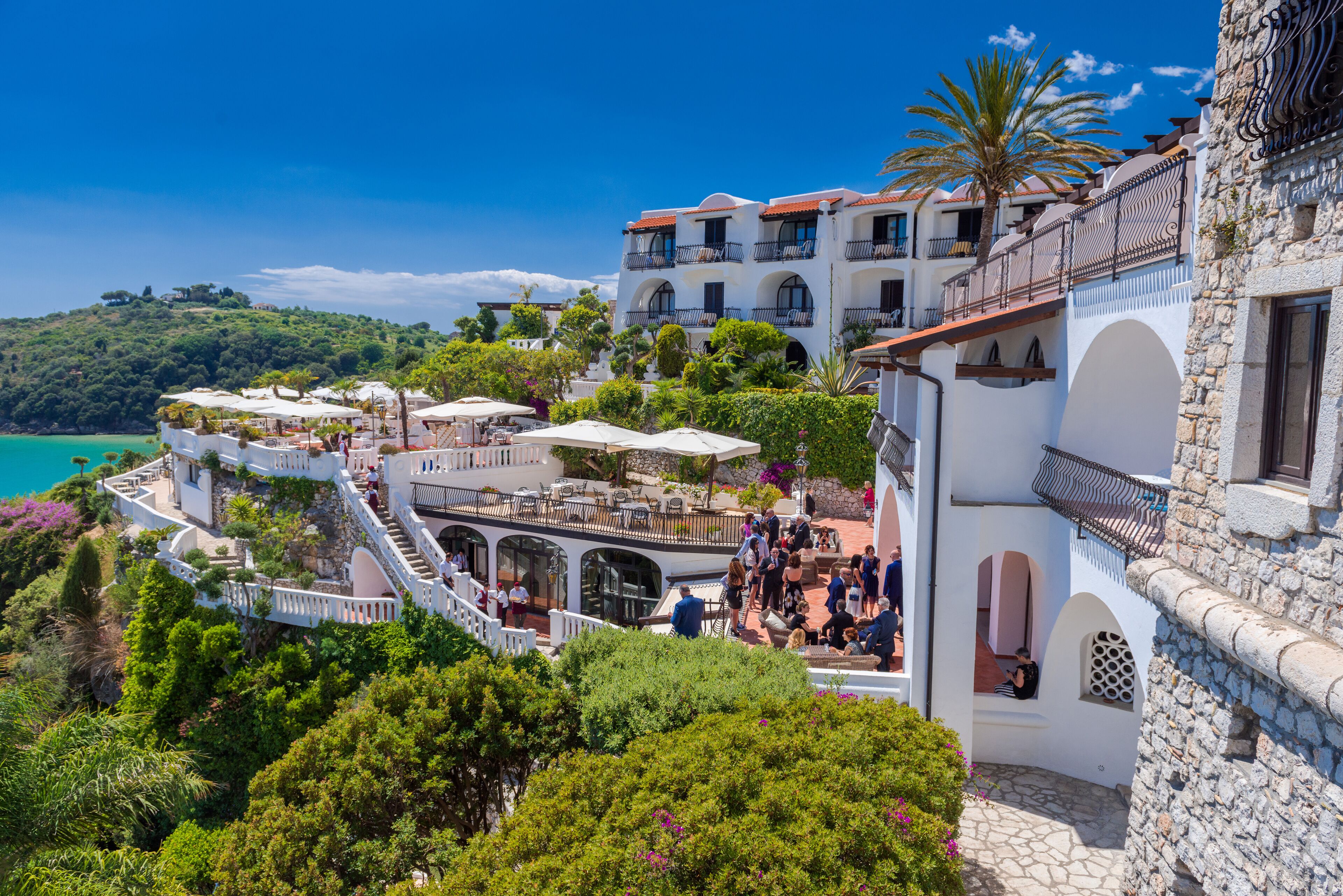 Ein Küstenhotel mit mehreren Balkonen, Außenbereichen zum Sitzen und Blick auf das Meer.
