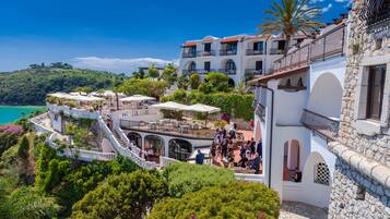 Ein Küstenhotel mit mehreren Balkonen, Außenbereichen zum Sitzen und Blick auf das Meer.