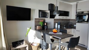 A modern kitchen with a flat-screen TV, a coffee machine, and a fruit bowl on the counter. - Welcome to apartment 64 in house 1 of the Vier Jahreszeiten complex (Großenbrode)