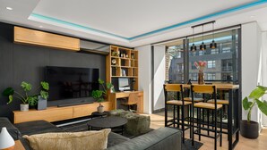 A modern living room with a flat-screen TV, wooden shelving, a dining area with chairs, and potted plants. - The Iron Works 611 (Cape Town)
