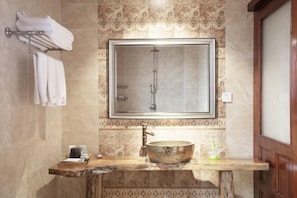 Un bany amb un mirall gran, un lavabo de fusta, un rentapeus i un portaTovellons.