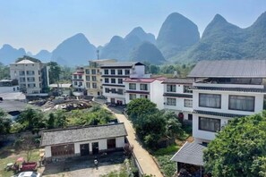 A residential area with multi-story buildings, a paved road, and a mountainous backdrop. - Xiaolonghe Hotel (Yangshuo Yulonghe Scenic Area) (Yangshuo)