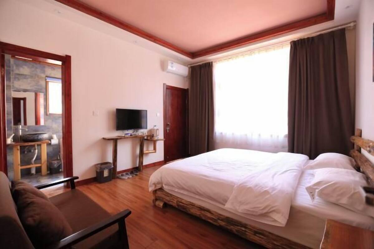 A bedroom with a bed, a TV, a desk, and a mirror.