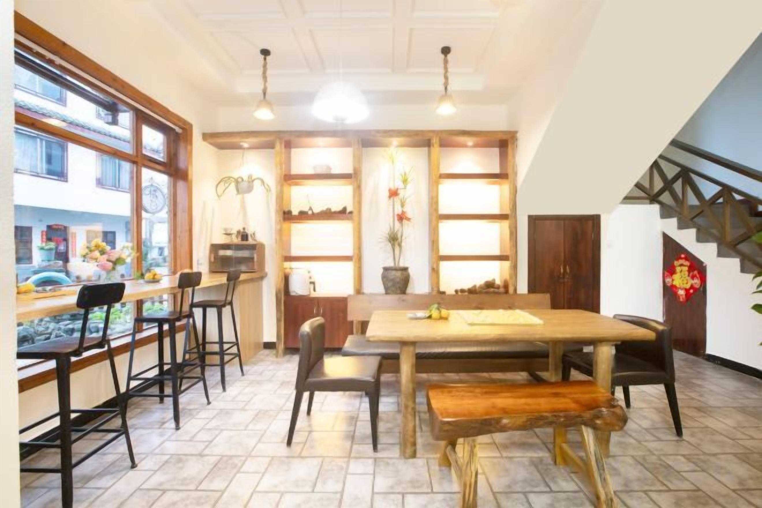 Un área de comedor con una mesa y sillas de madera, una barra y una escalera que conduce a un nivel superior.