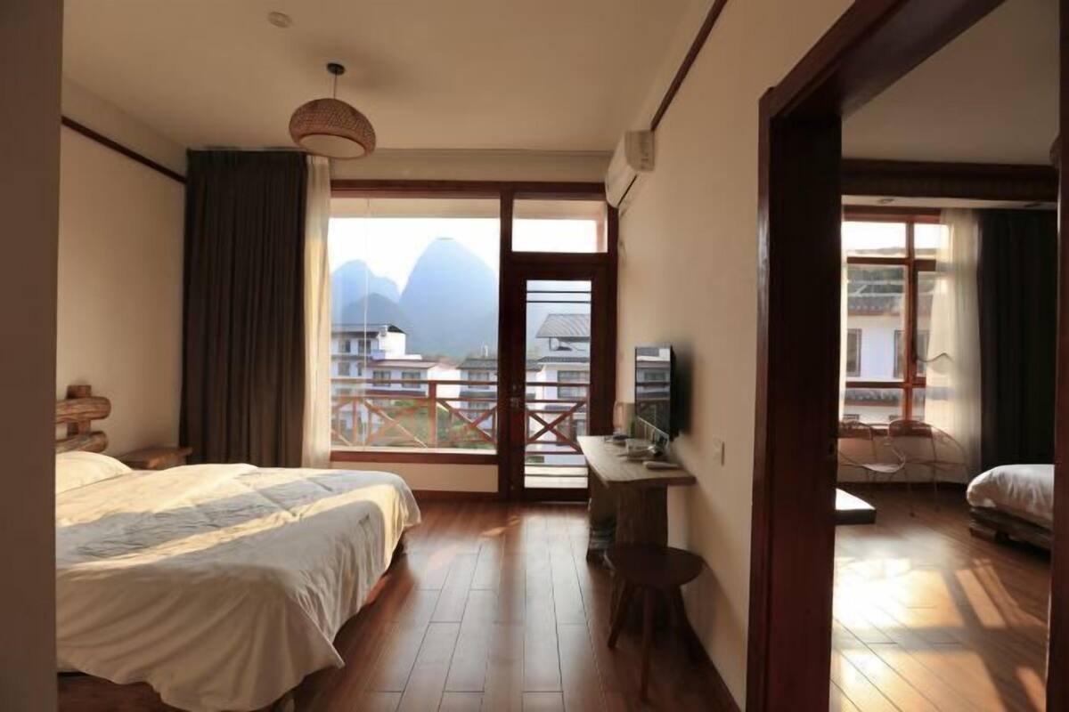 A bedroom with a bed, a desk, and a view of mountains.