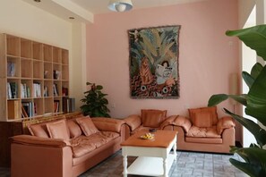 A living room with a sofa set, a coffee table, a bookshelf, and a large painting on the wall. - Xiaolonghe Hotel (Yangshuo Yulonghe Scenic Area) (Yangshuo)
